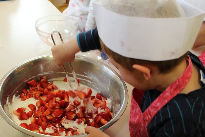 02IMG_0298_1200x800.jpg Kind mit Kochmütze rührt Erdberen in Süßspeise